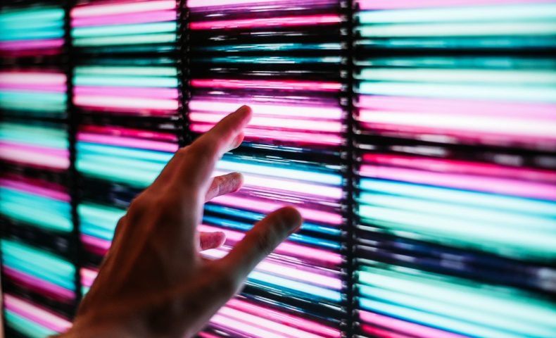 person s hand touching blue and pink led panel