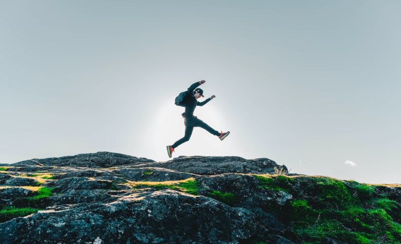 person on mid air above rocky hill