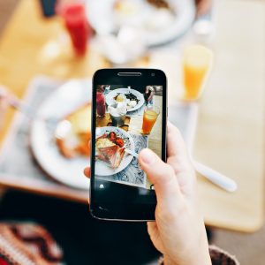 person holding phone taking picture of served food